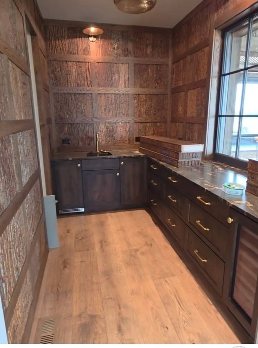 Custom butler's pantry with bark wall treatment, dark cabinetry, and brass hardware